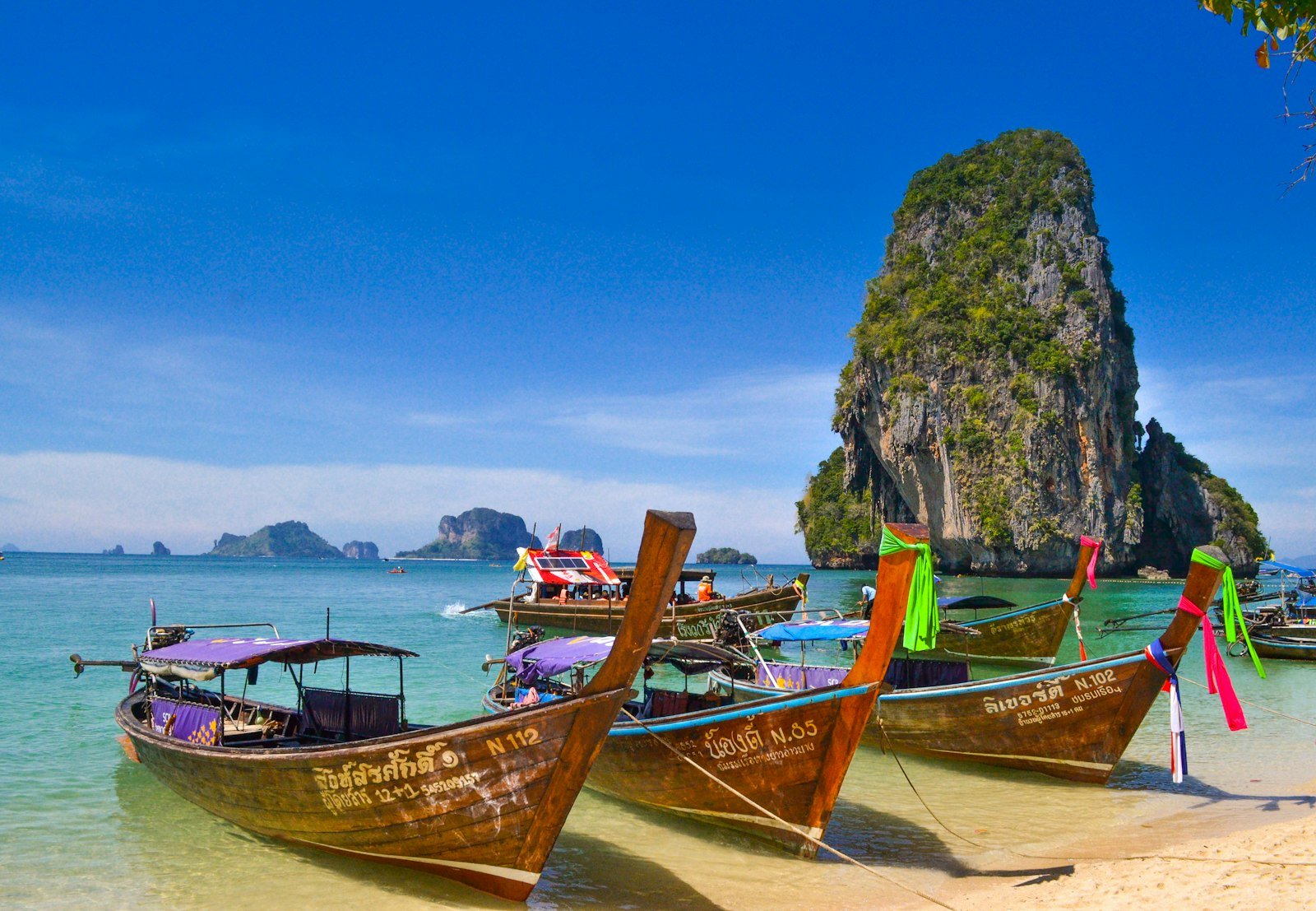 Traditional boats beside limestone islands in tropical Thailand