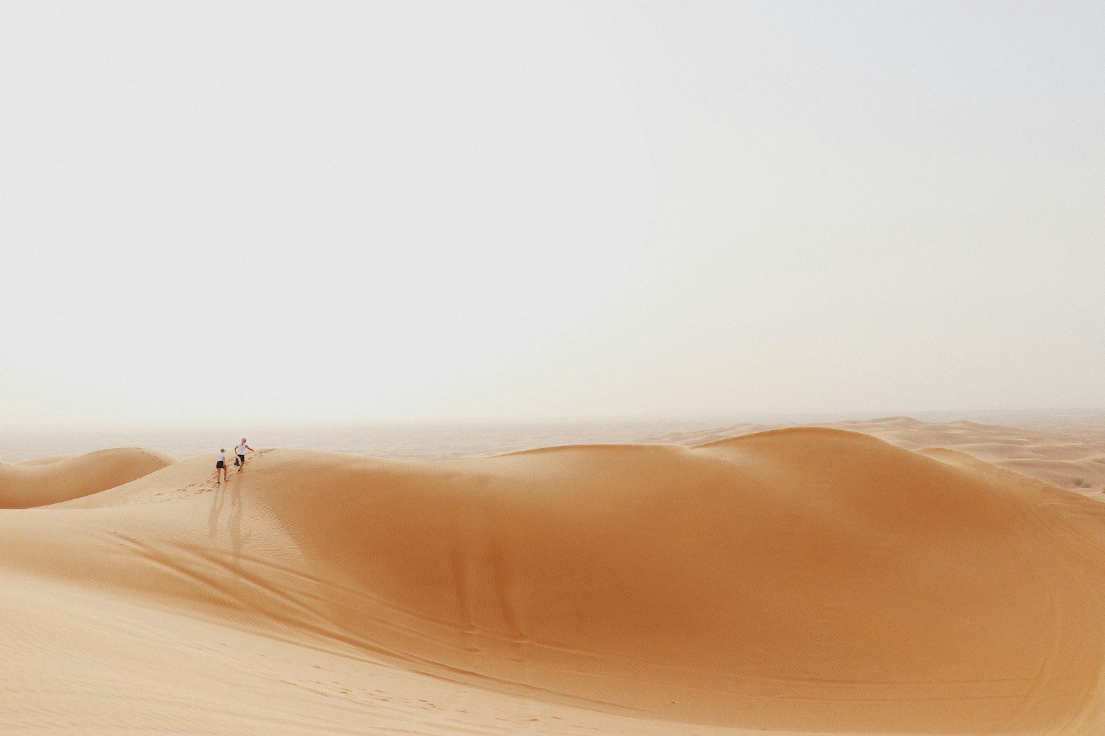 Travellers crossing a vast sand dune in the Dubai desert