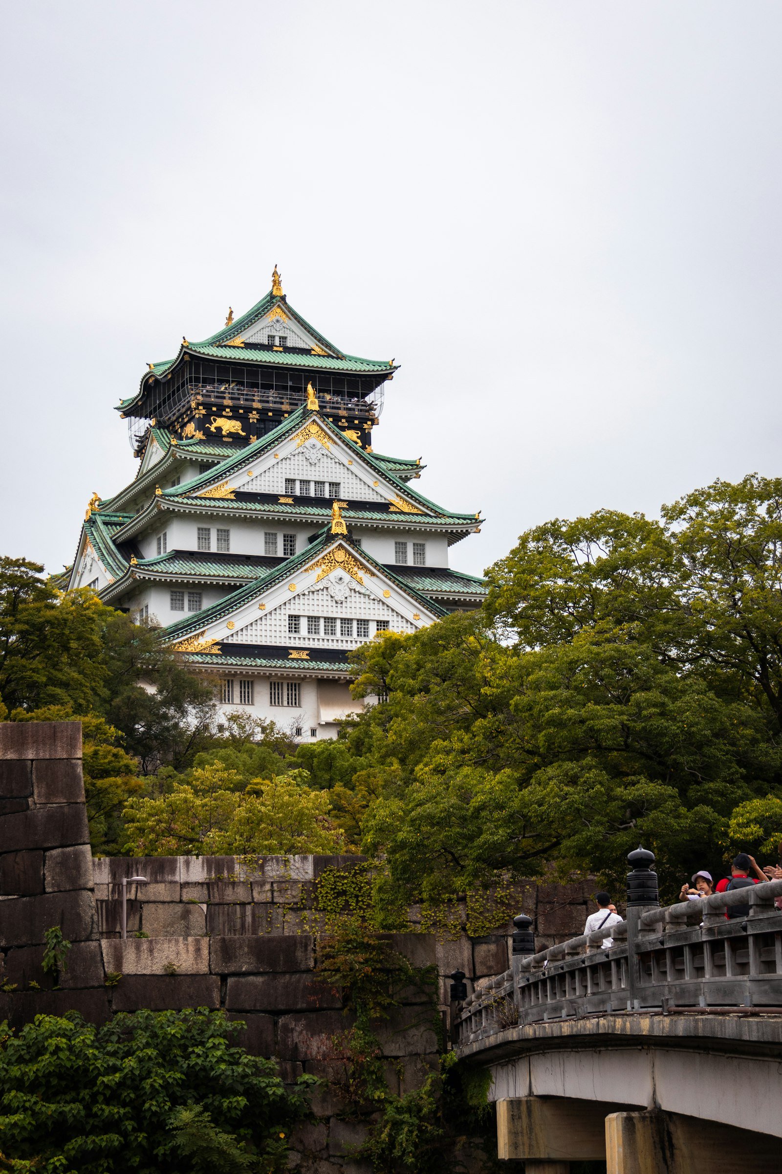 Osaka Castle rising above lush trees and historic stone walls, Japan